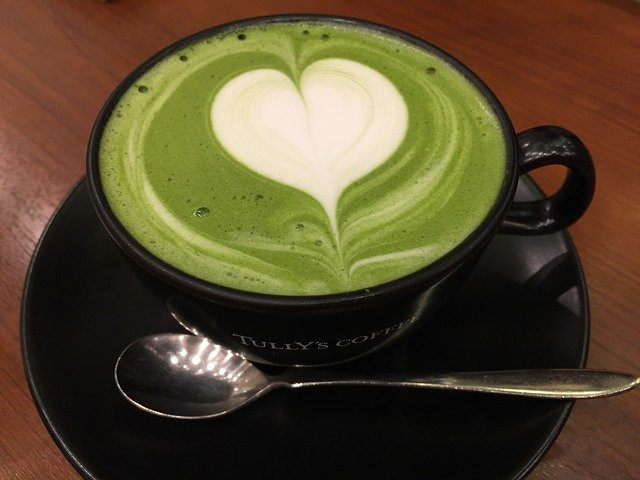 A cup of matcha latte with heart design 