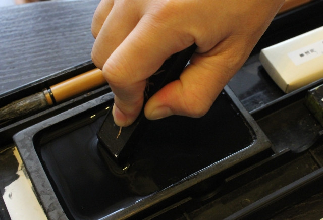 Man preparing ink for calligraphy on an inkstone