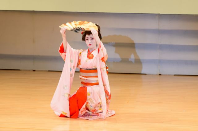 geisha performing traditional japanese dance with fan prop