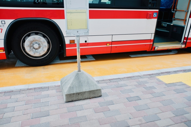 red bus stopped at bus stop to allow passengers to board/disembark